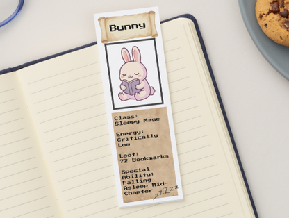 Bookmark with a cartoon bunny design on a notebook next to cookies and glasses.