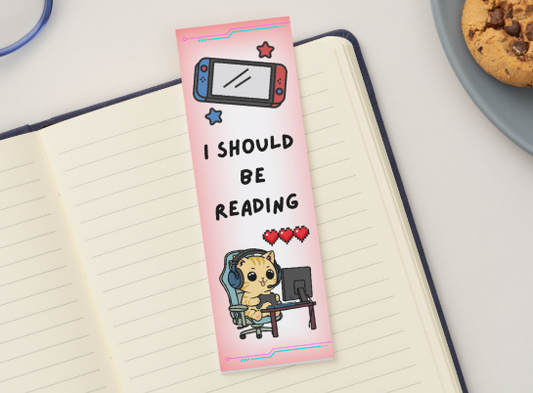 Pink bookmark with text and character design on a notebook with glasses and cookies in the background