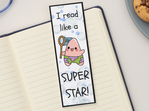 Bookmark with cartoon character and text 'I read like a super star!' on an open notebook.
